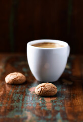 Amaretti (Italian biscuits) and cup of coffee on rustic wooden background. Close up. Copy space.