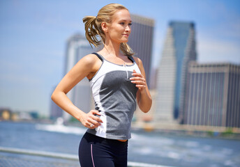 Jogging in the concrete jungle. Shot of an attractive blonde woman jogging in an urban setting.