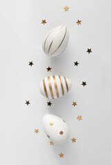 White Easter Eggs with Golden Lines and Dots on a White Background. Modern Easter Holiday Flatlay with White-Gold Eggs and Stars ideal for Banner, Card, Greetings. Top-Down View. No text.