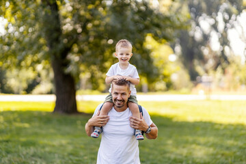 A happy father carry son on backs and spending day in nature on earth's day.