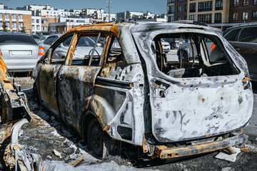 Burnt out minivan near with residential buildings. Destroyed by fire car for big family. Metal...
