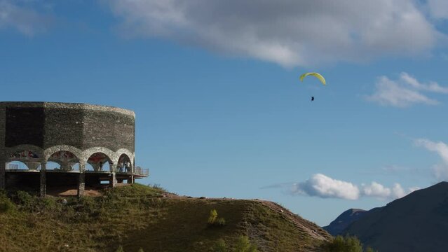 Paraglider flying next to the Friendship Monument in Gudauri, Georgia. Slow motion. Extreme sports activities concept.