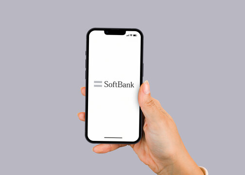 Female hand holding a smartphone iPhone 13 Pro with SoftBank Bank app on the screen. Gray background. Rio de Janeiro, RJ, Brazil. March 2022