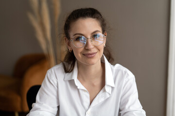 Portrait of a woman with glasses looking at the camera in a white shirt sitting in the office