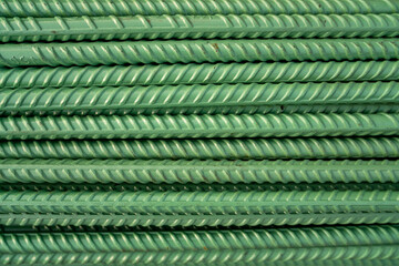 Green painted steel re-bar stacked up for use. High quality photo showing an interesting pattern.