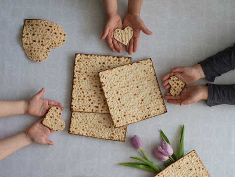 Children hands hold Matzah shape of heart. Traditional of Jewish Holiday on Passover. Home symbol of lovely family. top view, layout. love and care. Gift for lovers. big happy family in love