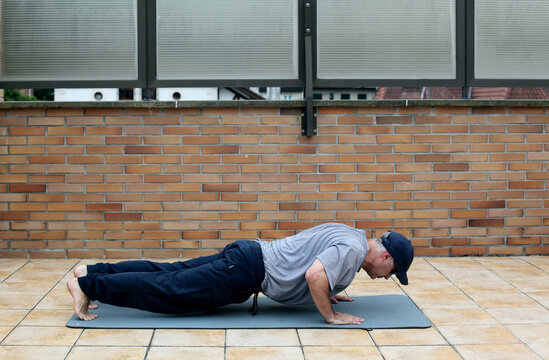 View Of A Mature Caucasian Man In Sportswear Doing Push Ups On Yoga Mat During Daytime