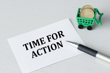A white card with time for action on a light table next to a pen and coins
