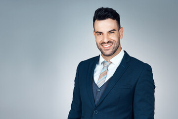 Confidence is his strongest trait. Studio portrait of a handsome young businessman posing against a grey background.