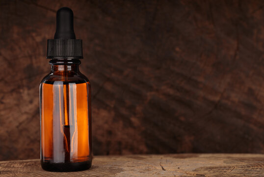 Cosmetic bottle with pipette on wooden table. Wooden beard oil in dropper. MOCKUP