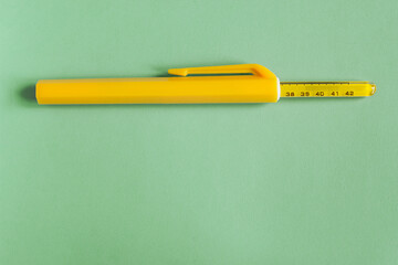 The top of an old mercury thermometer sticks out of its protective storage case on a colorful textured background with copy space. Objects and medical care.