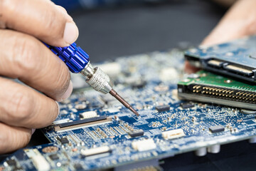 Technician repairing inside of printed circuit board PCB by soldering iron. Integrated Circuit. the...