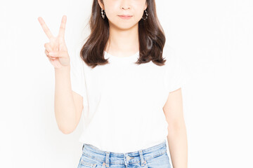 白い背景の前に立って、手で数字の2を表すTシャツを着ている若い女性