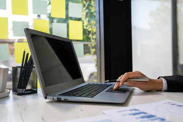 business woman using laptop analyzing graph document showing investment results and the operating...