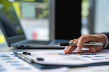 Fototapeta premium business woman using laptop analyzing graph document showing investment results and the operating results of the company