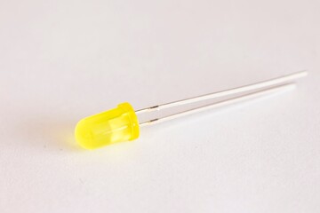 A top down studio portrait of a single yellow colored LED or color Light Emitting Diode lying on a white background, ready to be used in some kind of electronics PCB or circuit or print board.