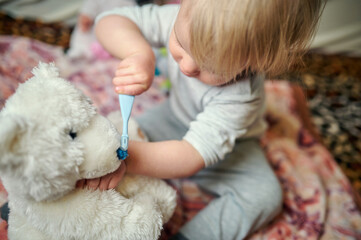 little girl brushes her teeth with a soft toy teddy bear. home atmosphere.