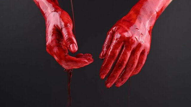 Women's hands in blood on a black background.