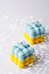 Two patriotic bubble candles - half blue, half yellow on white seamless surface with starry light shadows