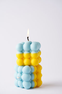 Two patriotic bubble candles stacked on each other - half blue, half yellow on white seamless surface