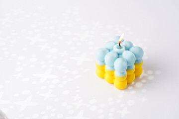 One patriotic bubble candle - half blue, half yellow on white seamless surface with starry light shadows
