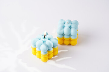 Two patriotic bubble candles - half blue, half yellow on white seamless surface with starry light shadows