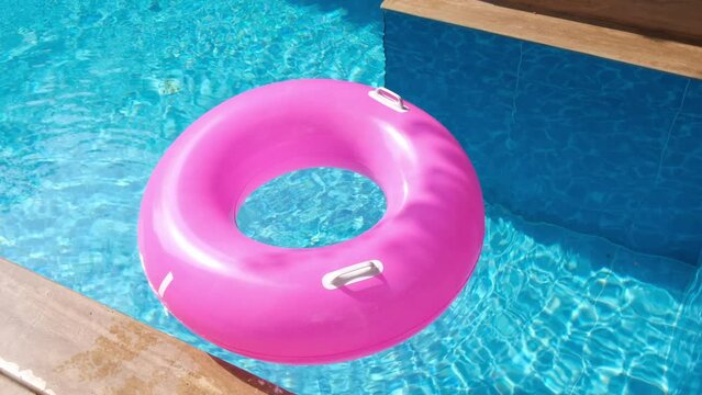 Pink inflatable ring floating in the swimming pool with blue water. Traveling and vacation concept
