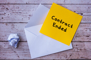 Contract ended text on yellow notepad with envelope background.