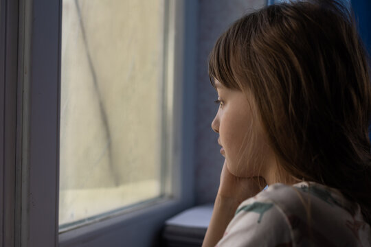 Little sad girl near window. Abuse of children concept