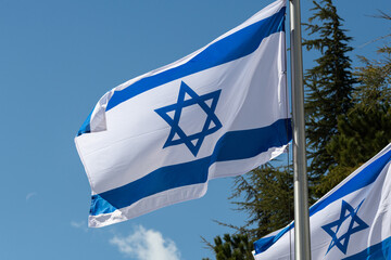 A blue and white, outstretched flag of the State of Israel on a pole in the Mt. Herzl military...