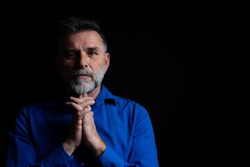 Beautiful bearded handsome man in low key studio. Portrait of a bearded man in a studio environment in front of a black background with dramatic low key lights.