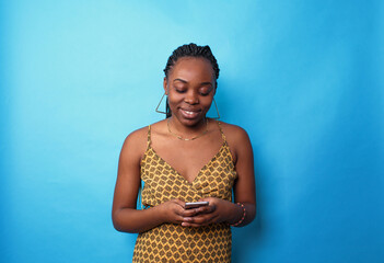 a picture of an African-American woman holding a mobile phone, enjoying pleasant conversations online on social networks, reading a funny article on the Internet on a blue isolated background.