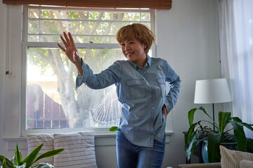 woman smiles with hand up by window