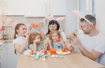 Obraz na płótnie Canvas Easter concept. Happy and loving mother and father are preparing a home decoration with their daughters for the Easter holidays
