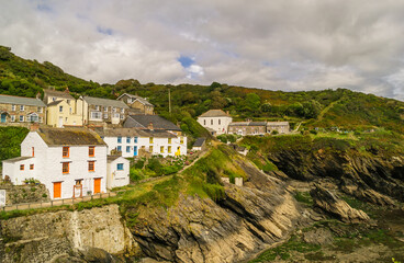 Fototapeta na wymiar The houses of Portloe on top of the cliffs overlooking the harbour and cove at low tide. Portloe is a traditional Cornish fishing village on the Roseland Coast.