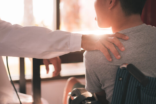 Hand of a kind doctor encourage to young man with disability in examination room, Activity in hospital ,home,quarantine,Symptom monitoring and consultation by a specialist,Healthcare concept.
