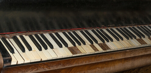 Fototapeta na wymiar Close-up of the keys of an old piano placed by a window to get warm from the sunlight in the morning. The most melodic musical instrument