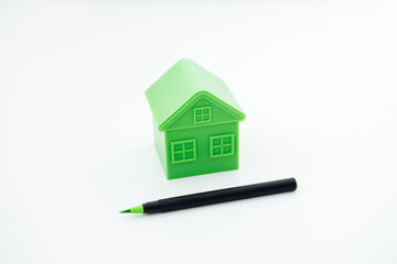 Greenwashing concept with green and black pen and plastic house. Greenwashing marketing ploy...