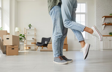 Happy people enjoying romantic moment in new home. Married couple kissing while unpacking in new...