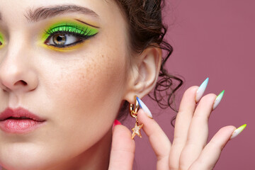 Young woman touches an earring in the form of a star on her ear.