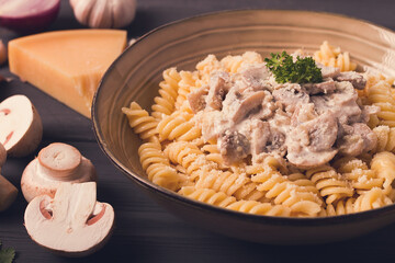Fusilli pasta, with champignons in cream sauce, top view, with ingredients, on a wooden table, no people,