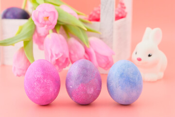 Beautiful pink tulips, rabbit toy and Easter eggs, pink, blue, light blue in a wooden white box. Pink background. Concept illustration of Easter, holiday. Greeting card. Close-up