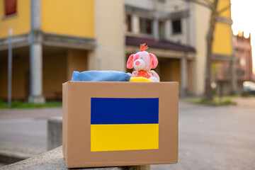 A box with a Ukrainian flag for donating humanitarian aid with things and children's toys for...