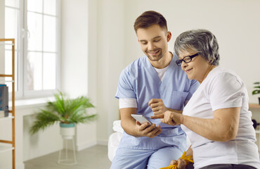 Caring male doctor showing his female senior patient how to download a useful health tracker app on...