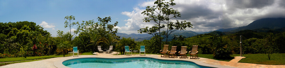 Beautiful Swimming Pool in the Costa Rican jungle landscape, surrounded by hills in this panoramic shot near Dominical. 