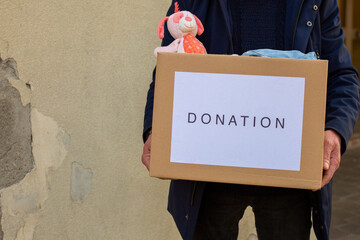 Volunteers hold in their hands a box of humanitarian aid with things and children's toys for the...