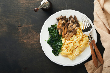 Omelet. Spinach oyster mushroom and cheese omelet or frittata on dark old wooden background. Breakfast idea.  Top view with copy space.