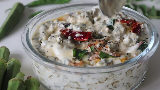 Garnishing ladies finger raita served in a glass bowl.