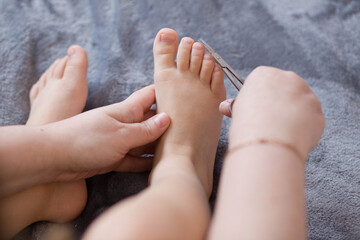 Mother cuts the child's toenails. Close-up. Mother cutting nails on feet of her kid