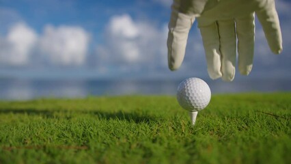 Hand in glove placing golf ball on tee